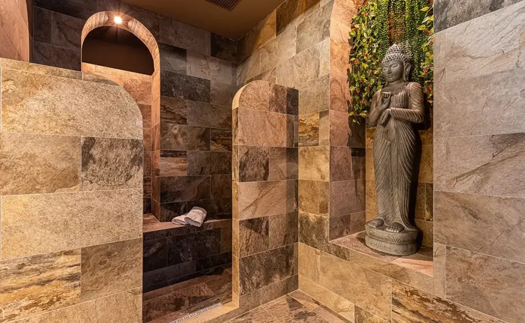 Private sensory shower with stone walls and a statue niche at The Queen's Rituals spa in Madrid